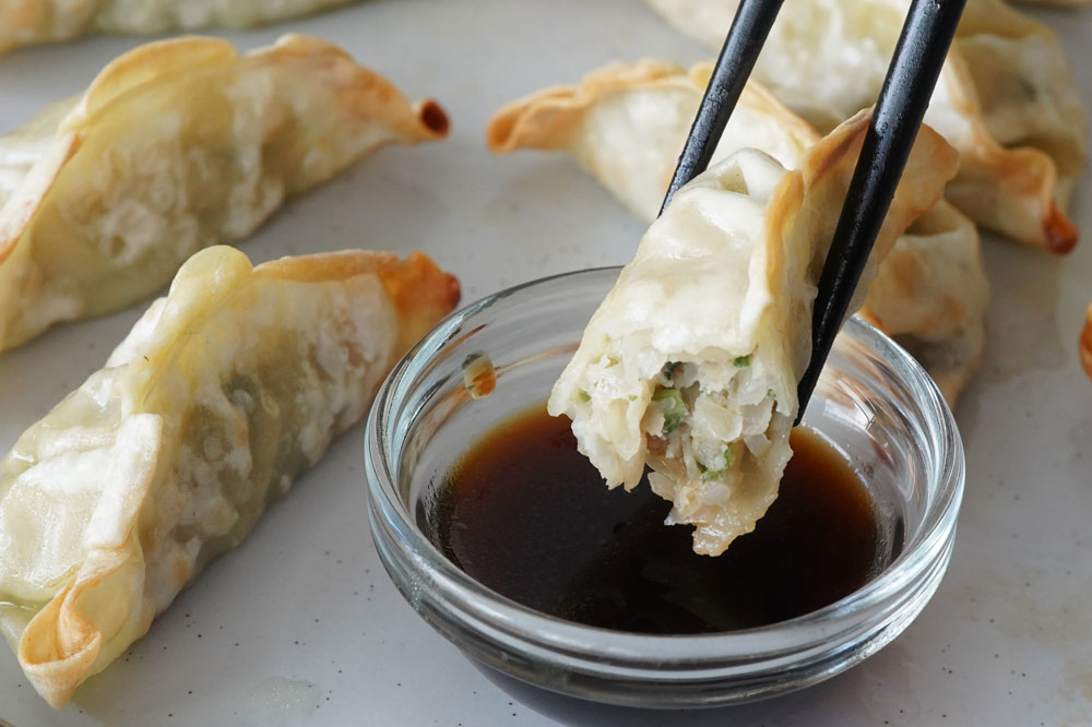 gyoza being dipped in soy sauce