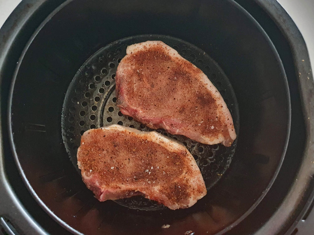 Raw pork chops in the air fryer basket