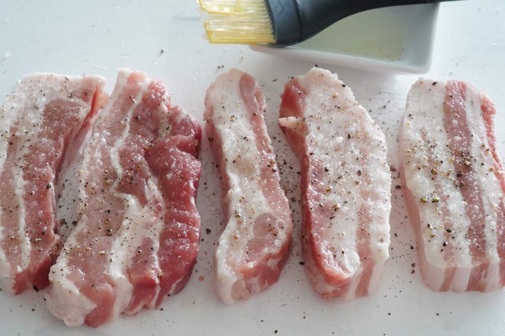 Seasoning raw pork belly strips