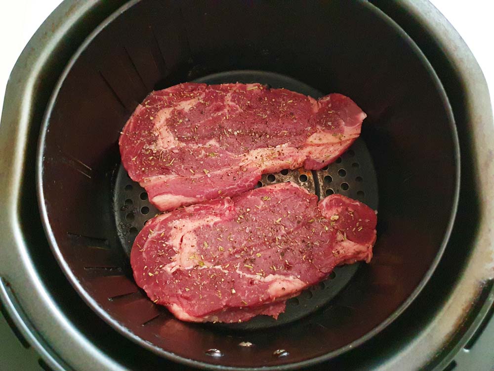 Raw sirloin steak in the air fryer basket