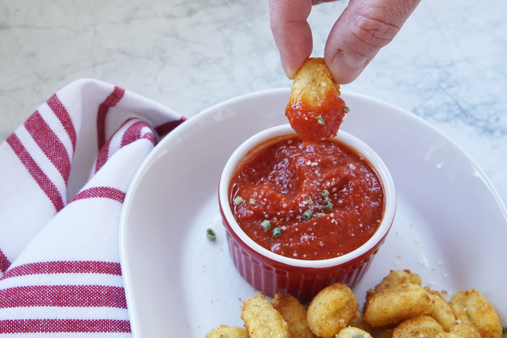 crispy gnocchi being dunked into dipping sauce