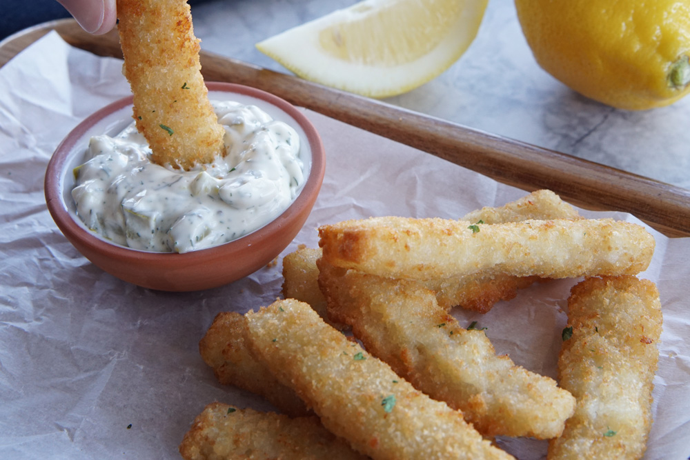 fish sticks with one being dipped in tartar sauce