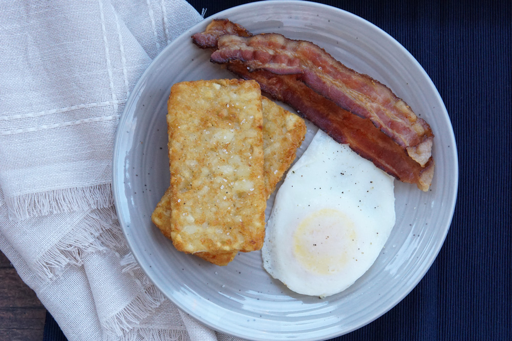 crispy hash browns on a plate with eggs and bacon