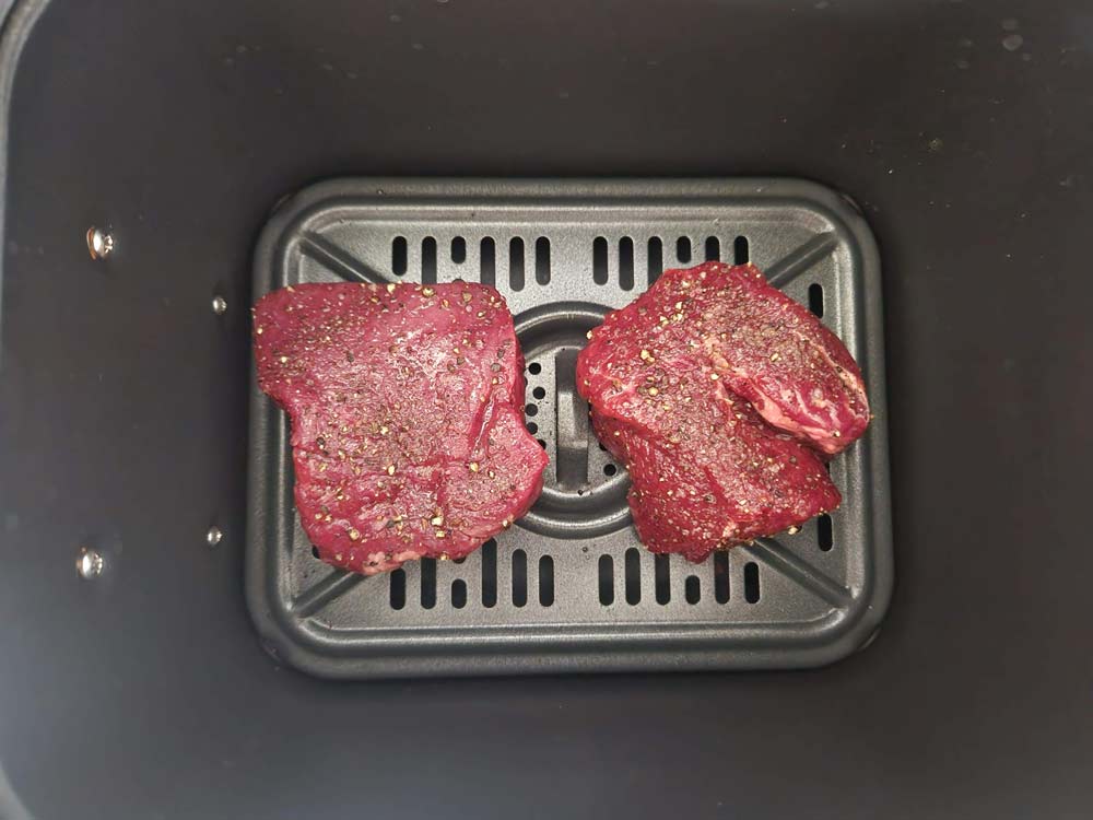 uncooked filet mignon in the air fryer basket