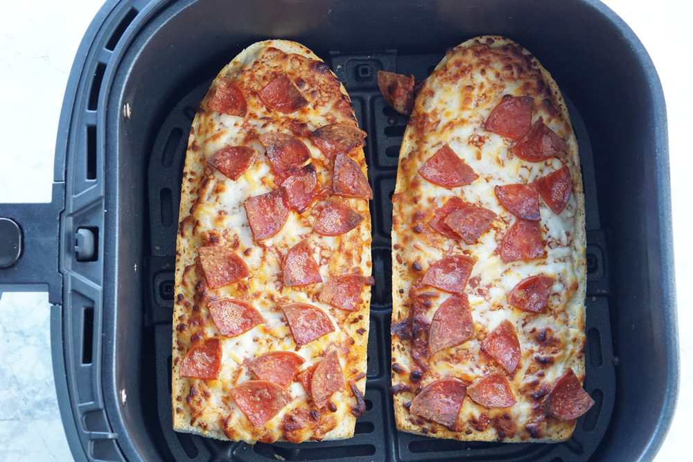 2 cooked French bread pizzas in the air fryer basket